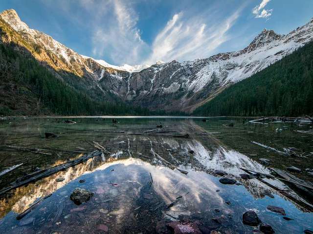 view of Avalanche lake from the water, looking forward to snow covered peaks