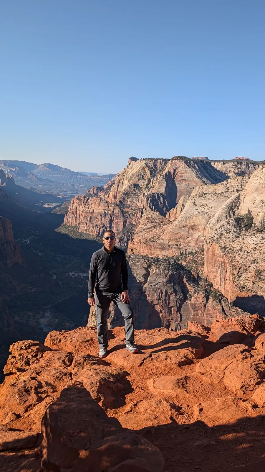 A hiker at the edge of Observation Point, Angels Landing behind