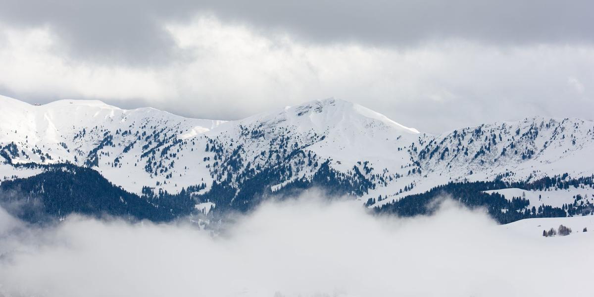 Snowy mountain ridges above fog and low clouds